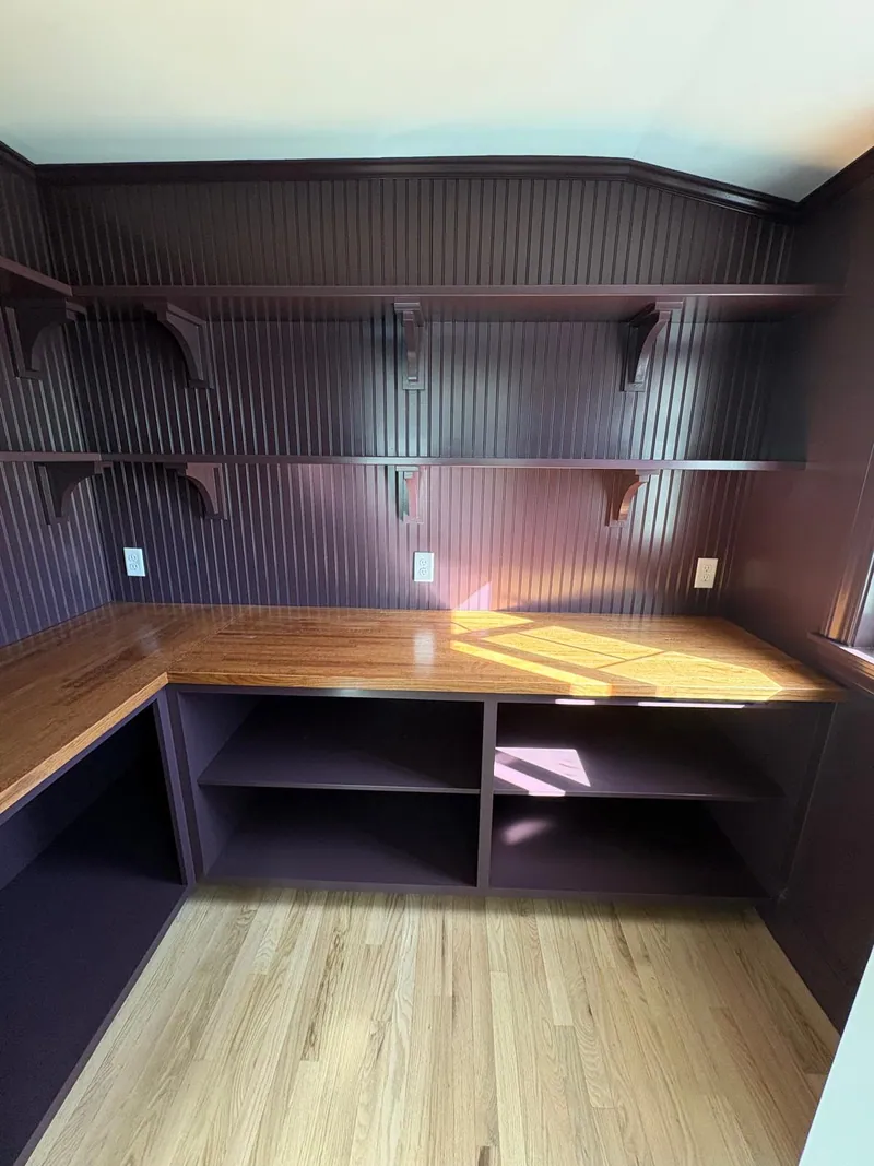 Home office painted in a deep plum with a built-in wood desk